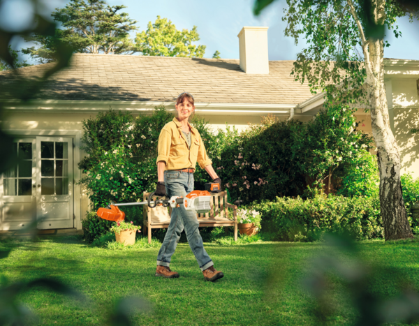Person mit Stihl Motorsense im Garten vor einem Haus
