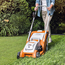 Person verwendet STIHL RMA 339 Rasenmäher in einem grünen Garten