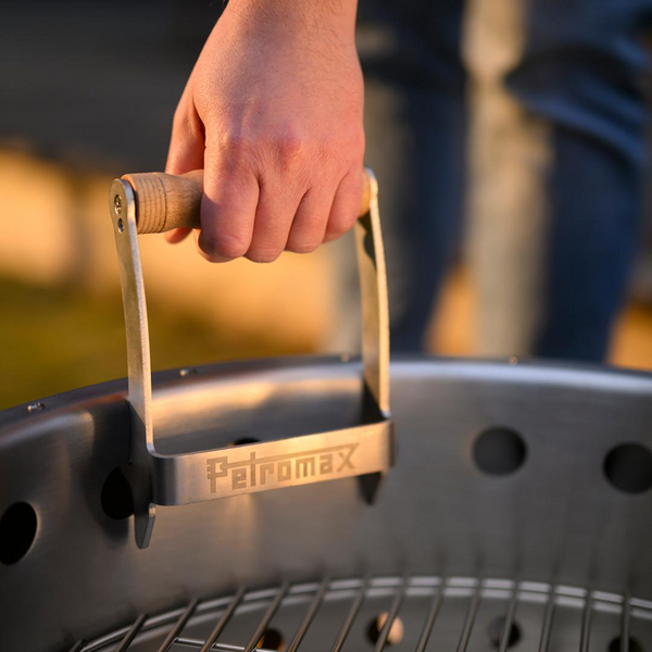 Hand hält Petromax Metallgriff bei Sonnenuntergang