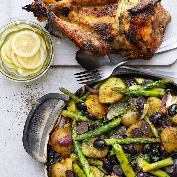 Gegrilltes Hähnchen mit gebratenen Kartoffeln Spargel Zwiebeln Oliven auf Holzbrett
