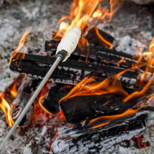 Stockbrot auf einem Petromax Spieß wird über Lagerfeuer gebacken