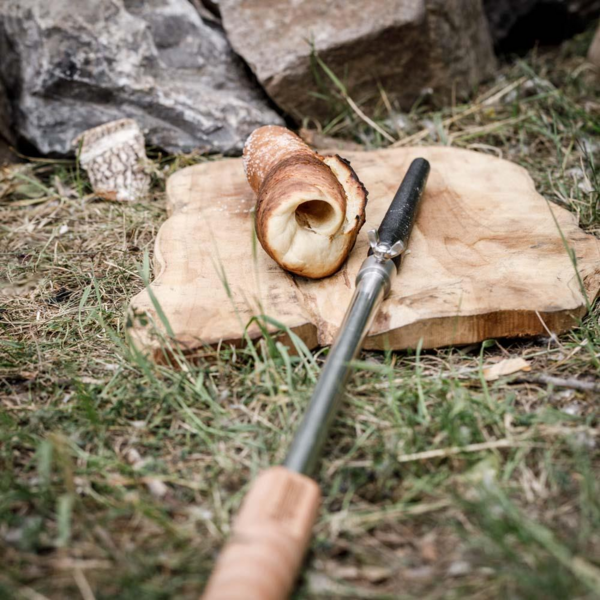 Petromax Stockbrot Spieß mit Gusseisenspitze und gebackenem Brot auf einem Holzbrett im Freien