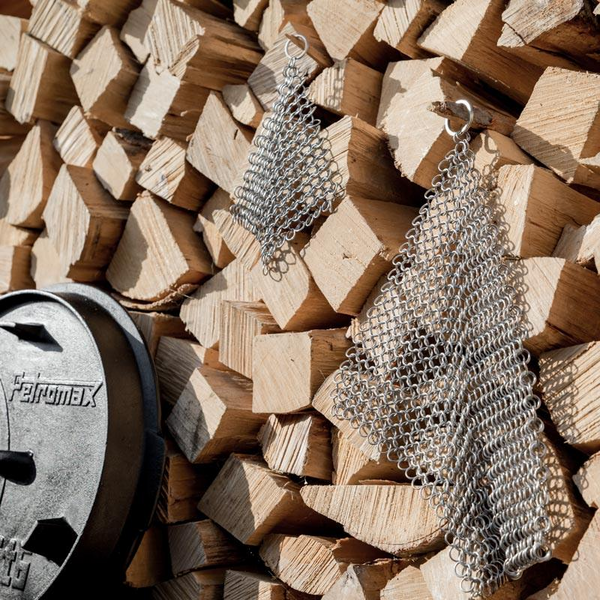 Zwei Petromax Ringreiniger XL auf einem Holzstapel neben einer gusseisernen Pfanne