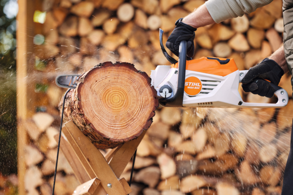 Person verwendet STIHL MSA 80 C-B Akku-Motorsäge zum Sägen eines Holzstamms