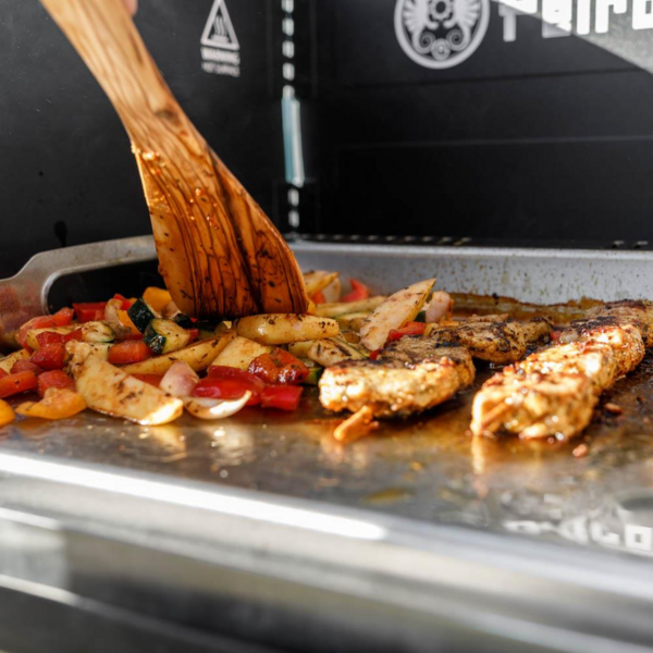 Plancha Grillplatte auf Petromax Gastisch mit gebratenem Fleisch und Gemüse im Freien