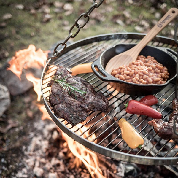 Petromax Hänge-Rost mit Steak und Bohnen über Lagerfeuer im Freien