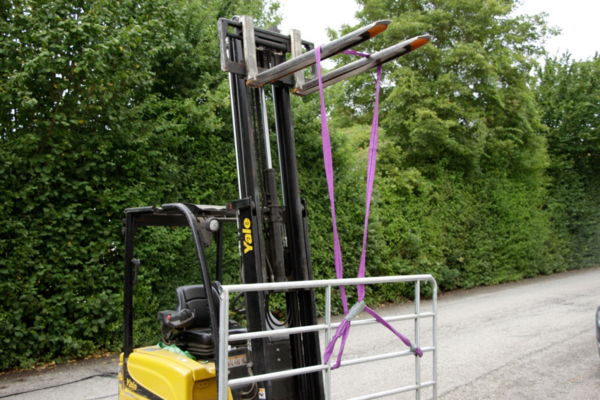Gelber Yale Gabelstapler mit lila Rundschlinge und Metallkonstruktion in natürlicher Umgebung