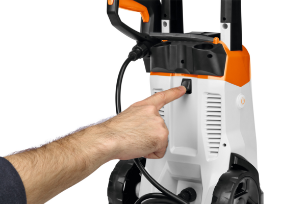Männliche Hand bedient Knopf an einem STIHL Spielzeug-Hochdruckreiniger in Weiß und Orange
