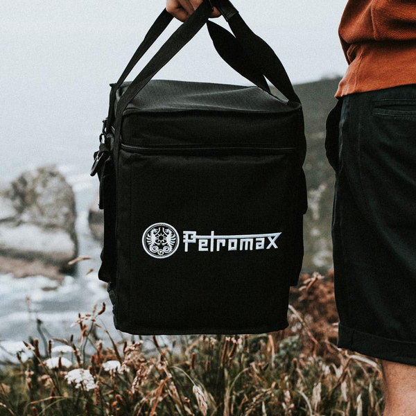 Person trägt schwarze Petromax Transporttasche für Raketenofen rf33 in natürlicher Umgebung