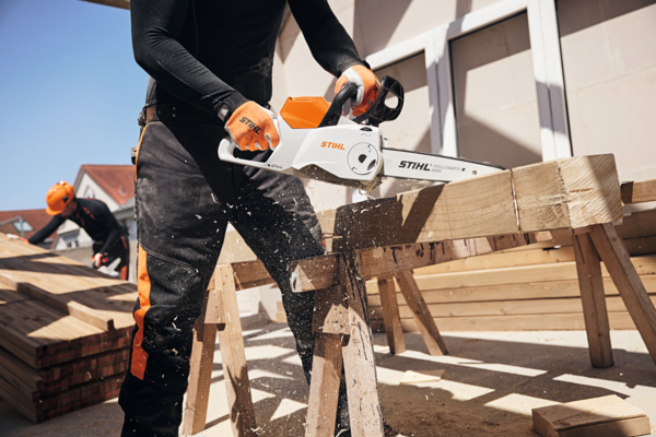Person verwendet STIHL Akku-Kettensäge zum Holzschneiden im Freien