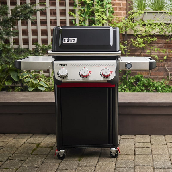 Weber SPIRIT EP-325 GBS Gasgrill auf einer Terrasse mit grüner Hecke im Hintergrund