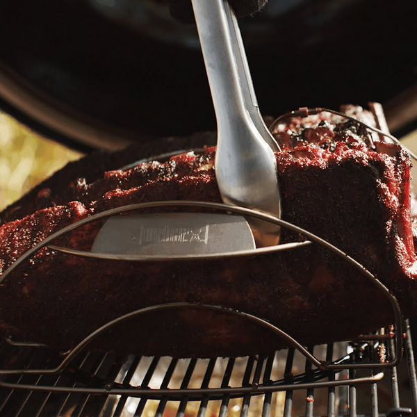 Saftige Spare-Ribs auf einem Weber Spare-Rib-Halter im Grill mit Zange