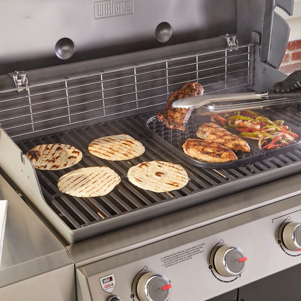 Weber Gasgrill mit verschiedenen Speisen, darunter Fladenbrot, Hühnerbrust und Gemüse