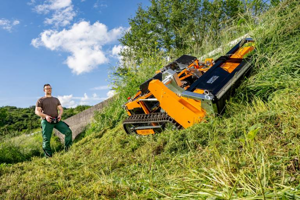 Mann steuert ferngesteuerten Mähroboter AS 1000 Ovis EVO RC auf geneigter Wiese