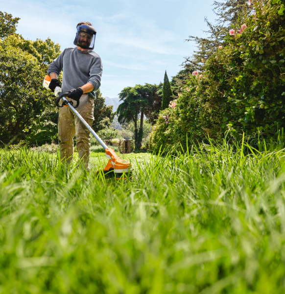Mann benutzt STIHL FSA 70 R Akku-Motorsense im sonnigen Garten