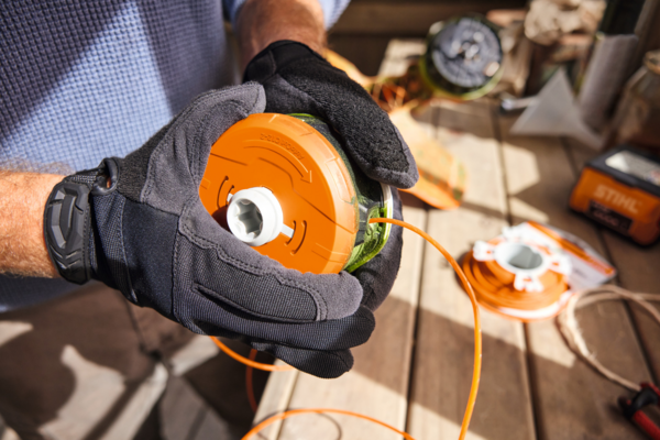 Person hält STIHL Mähkopf in Werkstatt