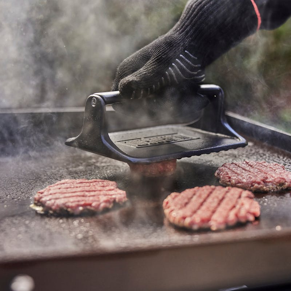 Person verwendet Weber Hamburgerpresse auf Grillplatte mit Burgerpatties und Dampf