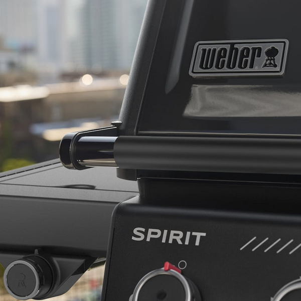 Nahaufnahme eines Weber SPIRIT EP-435R Gasgrills mit städtischer Skyline im Hintergrund