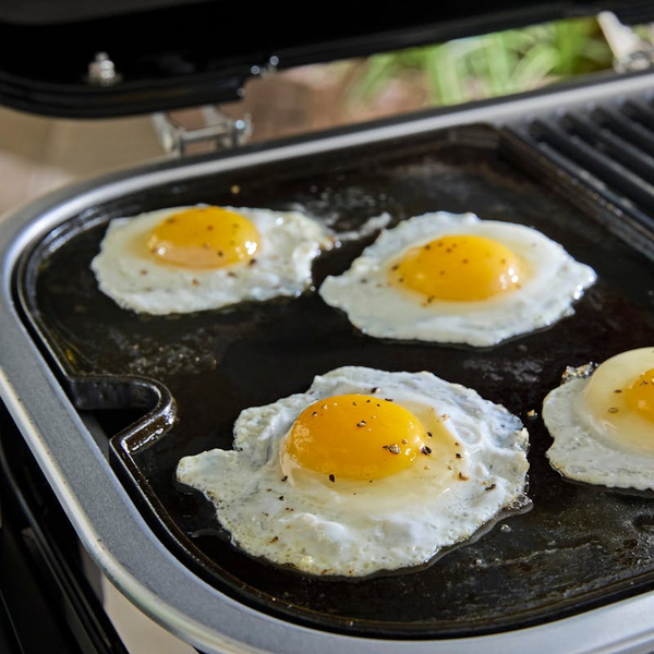 Spiegeleier auf Plancha-Grillplatte eines modernen Elektrogrills im Freien