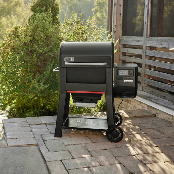 Weber SEARWOOD Holzpelletgrill in Schwarz auf einer Terrasse mit grüner Umgebung
