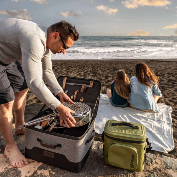 Mann öffnet Outdoor-Aufbewahrungsbox am Strand während Familie im Hintergrund entspannt