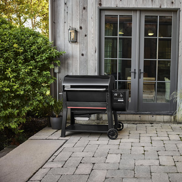 Weber SEARWOOD XL Holzpelletgrill vor einem modernen Haus mit Holzverkleidung