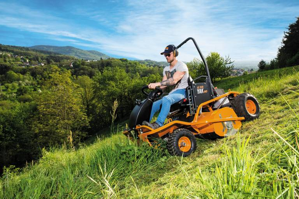 Mann bedient AS 1040 YAK 4WD Aufsitzschlegelmäher auf steiler grüner Wiese