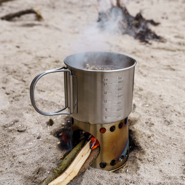 Petromax Kochbecher auf Sand mit brennendem Holz und Rauch