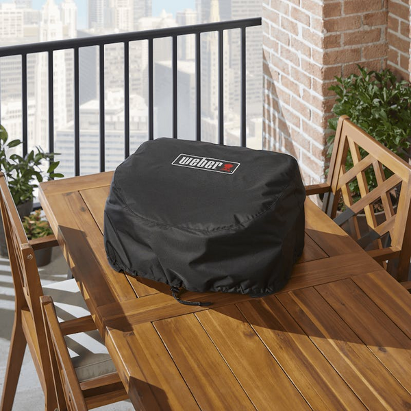 Weber Premium Abdeckhaube auf einem Elektrogrill auf einem Balkon mit Stadtblick