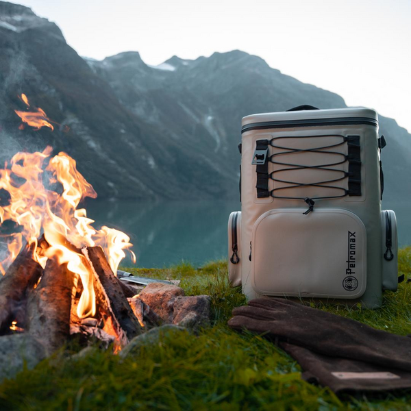 Petromax Kühlrucksack vor Lagerfeuer und Bergkulisse