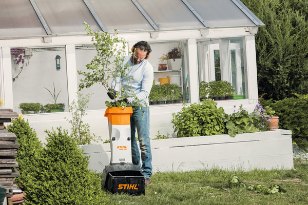 Mann verwendet STIHL Elektro-Häcksler GHE 105 im Garten