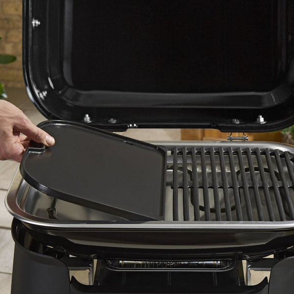 Hand setzt Plancha-Einsatz auf Weber LUMIN Elektrogrill
