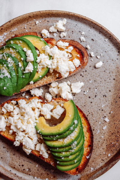 Geröstetes Brot mit Avocado und Feta, bestreut mit Murray River Salz auf rustikalem Teller