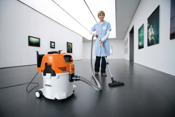 Frau in blauer Uniform verwendet STIHL SE 122 Sauger in Kunstgalerie