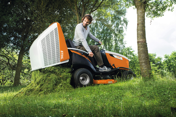 Mann zeigt Grasfangkorb eines STIHL RT 6112 ZL Aufsitzmähers in natürlicher Umgebung