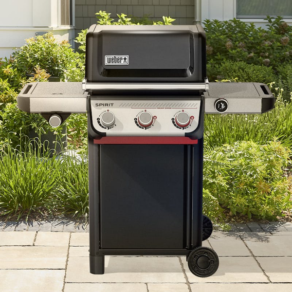 Weber SPIRIT EX-335 Gasgrill auf einer Terrasse mit geschlossener Haube und umgebender Vegetation
