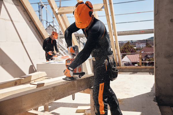 Zwei Männer sägen Holz auf Baustelle mit STIHL Akku-Kettensäge