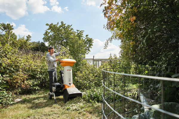 Mann verwendet STIHL GH 460 Häcksler in sonnigem Garten