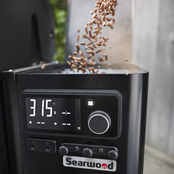 Holzpelletgrill mit einfallenden Buchenholzpellets und digitaler Temperaturanzeige
