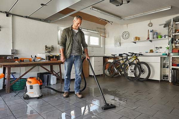 Mann benutzt Stihl SE 33 Nass- und Trockensauger in einer organisierten Garage