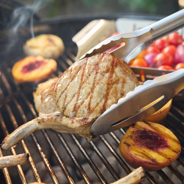 Gegrilltes Kotelett und Pfirsiche auf einem Holzkohlegrill im Freien