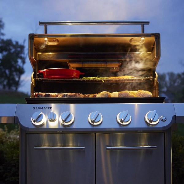 Weber Summit FS38 S Gasgrill in Betrieb mit geöffnetem Deckel und sichtbarem Grillgut bei Dämmerung