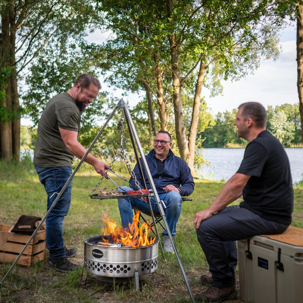 Drei Männer genießen ein Grillfest am See mit einer Petromax Feuerschale Tyropit