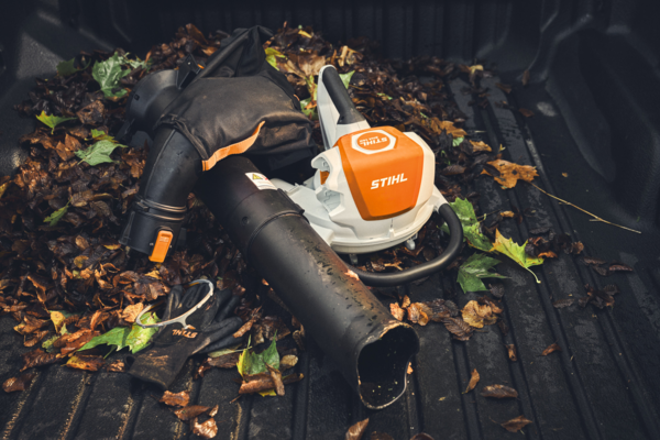 STIHL SHA 140 Akku-Saughäcksler mit Zubehör in Fahrzeugladefläche umgeben von Herbstlaub