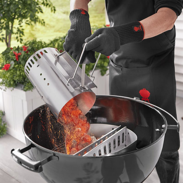 Person verwendet Weber Anzündkamin zum Befüllen eines Grills mit glühender Kohle im Garten