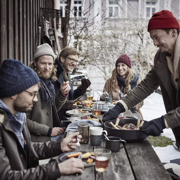 Gruppe von fünf Freunden genießt Wintergrillen im Freien an einem Holztisch