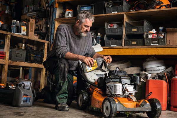 Älterer Mann wartet STIHL Rasenmäher in Werkstatt