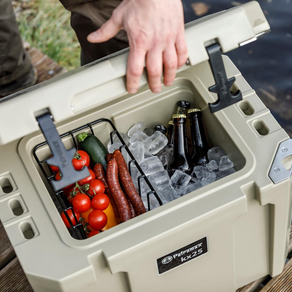 Hand öffnet Petromax Kühlbox kx25 mit Einsatzkorb voller Gemüse Würstchen Eis und Bier
