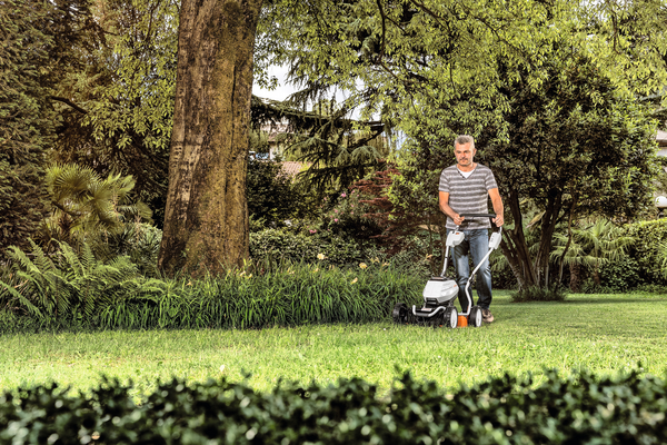 Älterer Mann benutzt STIHL Akku-Mulchmäher im grünen Garten