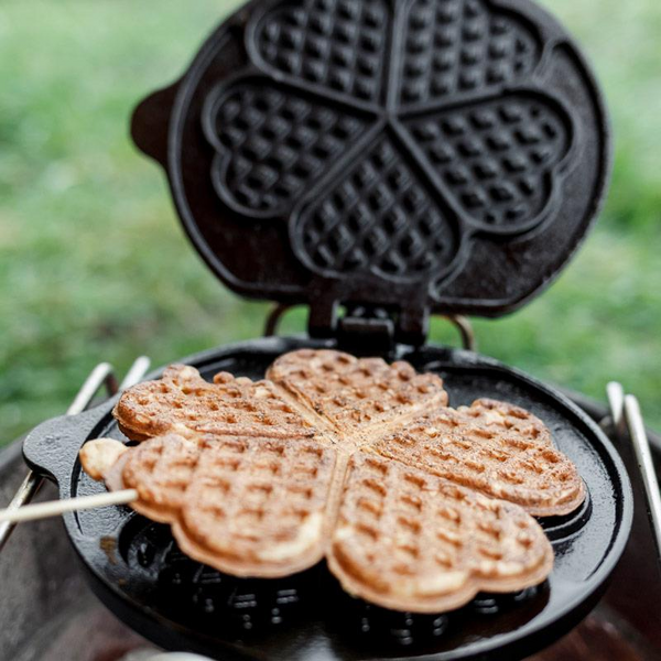 Petromax Waffeleisen mit zwei herzförmigen Waffeln auf einem Grill im Freien